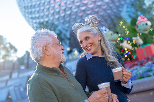 Mature couple walking and enjoying a hot chocolate in Epcot at Christmas time