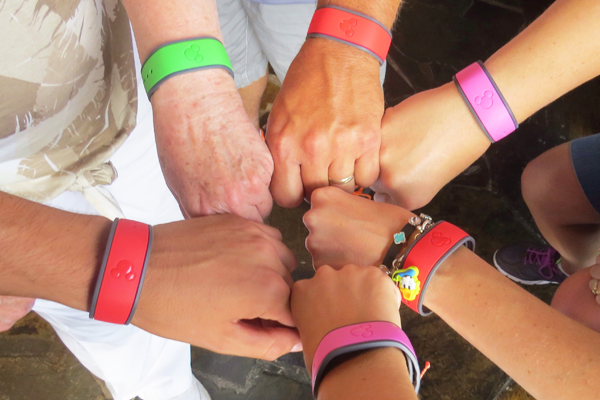 Hands grouped together all wearing magic bands