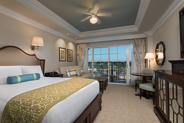 Inside Disney's Grand Floridian Villas studio room with queen bed, sofa, table and balcony