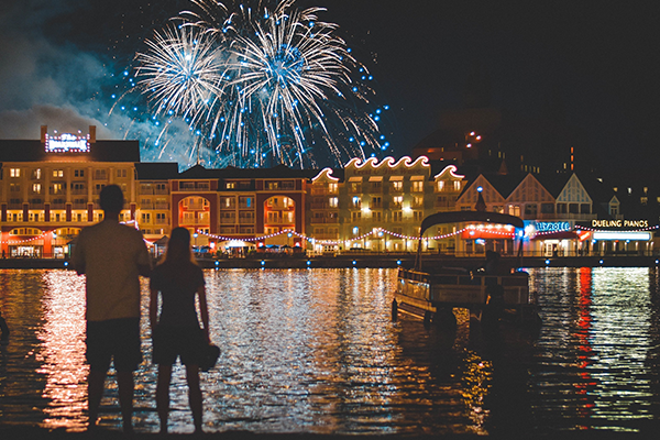Couple and boat on Crescent Lake watching Fireworks over Disney's Boardwalk Resort