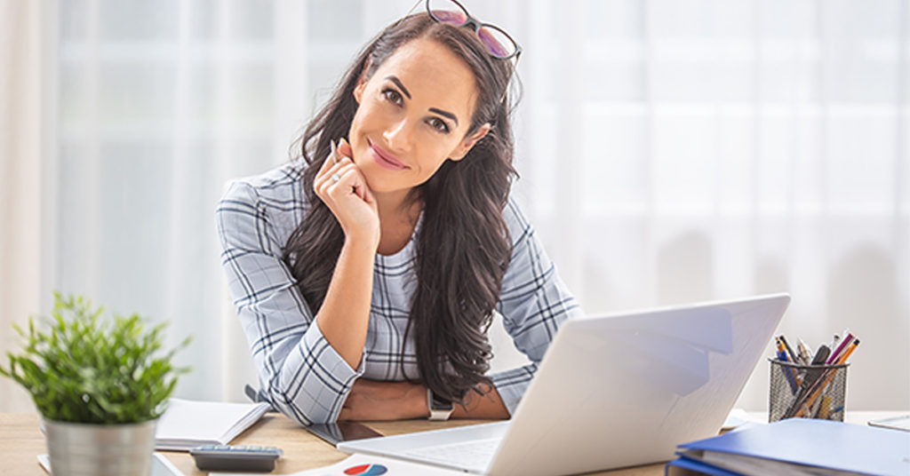 Smiling business woman at desk with laptop