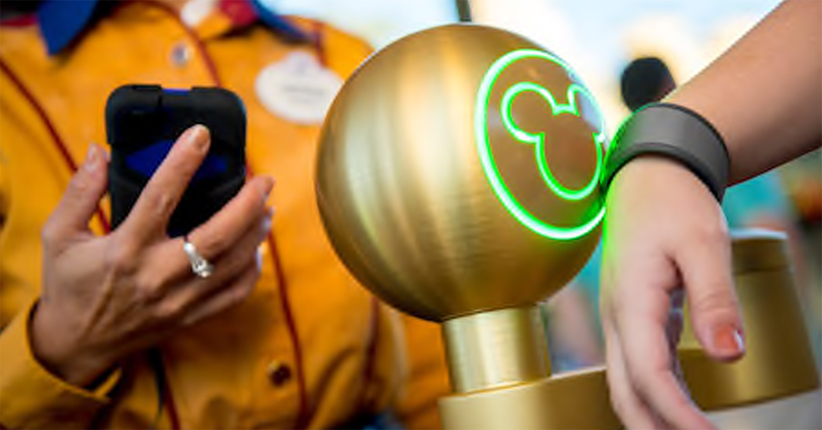 person tapping magic band to reader with Disney cast member