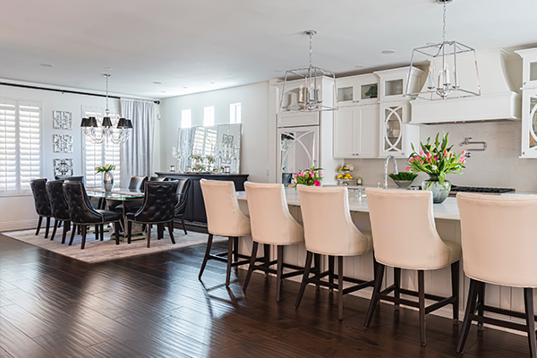 Open concept kitchen and dining room with white cabinets, dark wood floors and large island with seating for 5