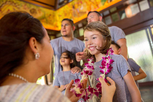Woman greeting family and placing flower lei on girl